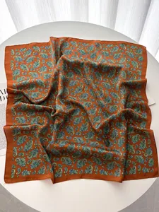 Detail showing paisley silk scarf in brick red with intricate floral patterns on a table