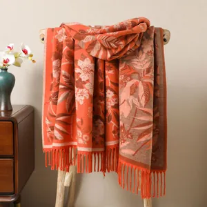 Détail d'un châle jacquard rouge à motifs floraux avec franges sur support bois