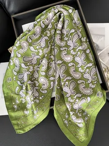 Détail d'un foulard en soie verte avec motif cachemire, étoiles et bordure soleil