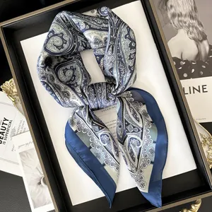Foulard di seta satinata blu con motivo paisley annodato su un vassoio da esposizione