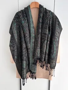Détail d'un châle vintage à motif cachemire avec franges noires sur un cintre