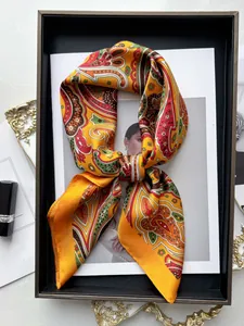 Detail of vintage paisley silk scarf with vibrant orange tones on a luxury display tray