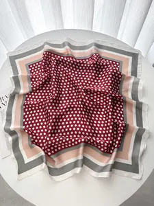 Detailed close-up of dark red polka dot silk scarf draped over a magazine and white table