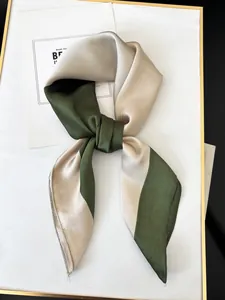 Detail of silk-like satin headband showing green and gold color block with knotted texture