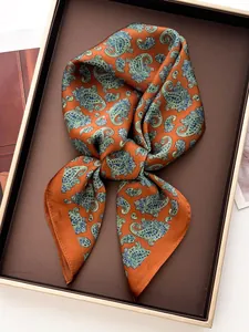 Detail of a silk satin square scarf with paisley pattern in warm orange gift box