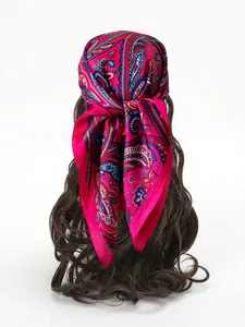 Detail of rose red paisley silk scarf knotted on a model with glossy satin texture