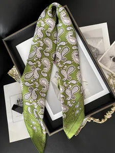 Détail d'un foulard en soie verte avec motifs paisley drapé sur un cadre élégant
