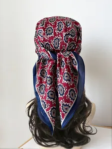 Detail of burgundy paisley silk scarf tied as a headband on wavy brown hair