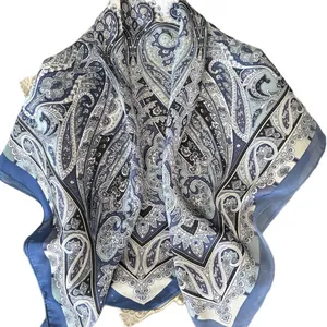 Elegante sciarpa in seta con motivo paisley blu esposta su un vassoio decorativo classico