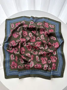 Detailed close-up of paisley pattern silk square scarf on white table with soft lighting