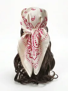 Détail d'un foulard en soie avec motifs paisley rouges classiques sur tissu beige