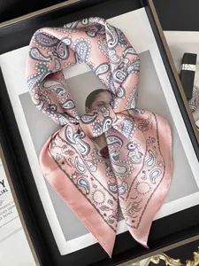 Détail d'un foulard en soie rose à motif cachemire avec bords roulés sur un cadre