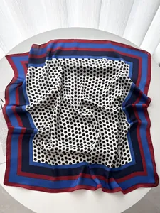 Detailed view of polka dot silk scarf with multi-colored striped borders on white table