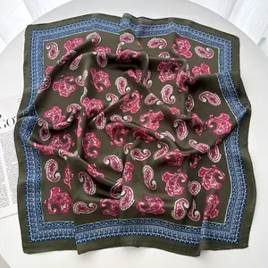 Close-up of olive silk-like square scarf with pink paisley pattern and geometric border