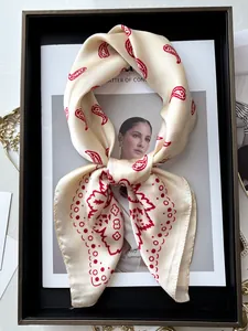 Détail d'un foulard soyeux avec motif paisley rouge sur un tissu couleur champagne