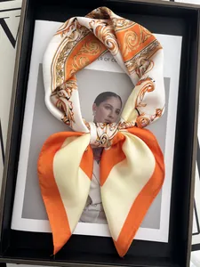 Close-up of silk square scarf tied in a bow with vintage baroque prints in orange and yellow