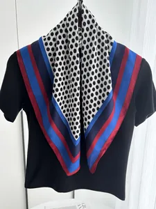 Detailed view of polka dot silk scarf with contrast border on a black shirt