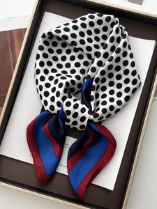 Detailed view of polka dot silk scarf with color-block stripes on a presentation tray