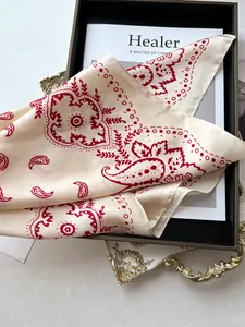 Détail d'un foulard en soie cachemire rouge avec texture brillante sur plateau déco