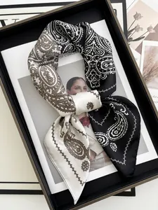 Close-up of paisley silk scarf in black and beige displayed on a tray over a magazine