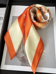 Close-up of orange and beige striped silk scarf with baroque patterns on magazine