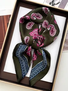Detail view of olive green paisley silk scarf with elegant pattern in a gift box setup