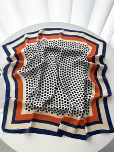 Polka dot silk scarf with vibrant geometric patterns laid flat on a round white table
