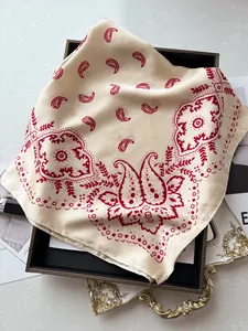 Détail d'un foulard en soie à motif paisley rouge sur un plateau noir et marbre chic