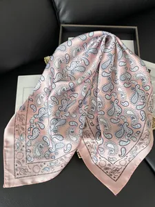 Détail macro d'un foulard en soie rose avec motifs paisley bleus et reflet satiné