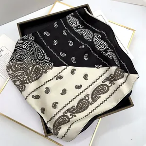 Close-up of black and white paisley silk scarf with satin finish on elegant display tray
