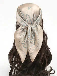 Détail d'un foulard en satin beige à motif paisley bleu porté comme accessoire de cheveux