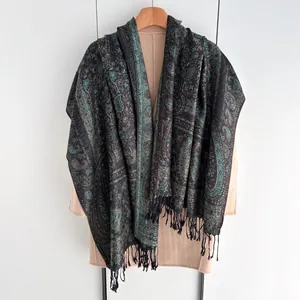 Châle ethnique cachemire vert foncé et doré avec franges noires sur un cintre