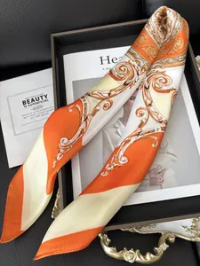 Detailed close-up of an orange and beige silk scarf with baroque floral patterns and sheen