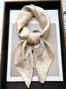 Détail macro du foulard en soie champagne à motifs paisley verts noué avec élégance