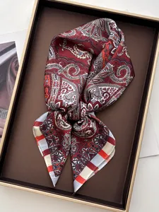 Detail shot of a paisley silk scarf in deep red and brown tones on a luxury tray