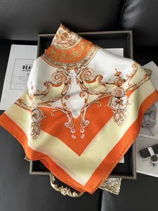 Detail of luxury orange silk scarf with baroque scroll patterns on a black leather tray