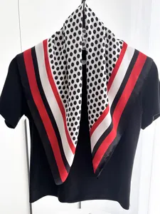 Detailed view of polka dot silk-feel scarf with red and black stripes draped on a shirt