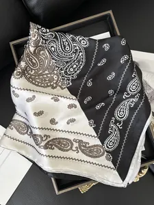 Detailed macro view of black and white paisley silk-like scarf with 100% polyester fabric texture