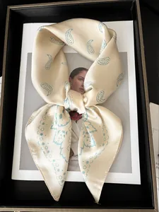 Gros plan d'un foulard en soie beige au motif paisley bleu sur un magazine