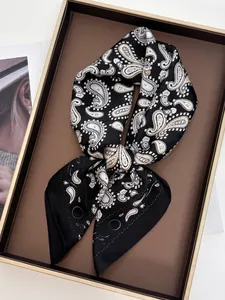 Détail d'un foulard en soie noir avec motif cachemire doré noué en nœud papillon