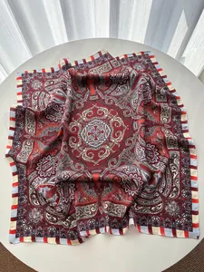 Detail of red paisley silk square scarf showing intricate bohemian pattern and glossy texture