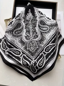 Detail view of a French retro silk scarf with black and white paisley pattern on marble