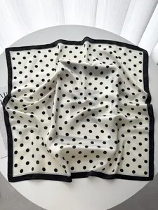 Close-up of silk-like polka dot square scarf draped elegantly on a white surface