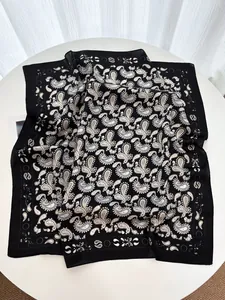 Détail d'un foulard en soie noir et blanc à motif paisley sur une table ronde