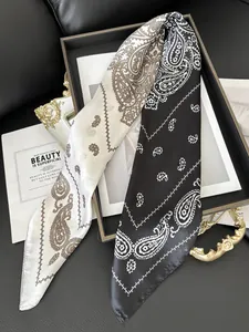 Detail of silk satin scarf featuring classic paisley patterns in black and beige contrast