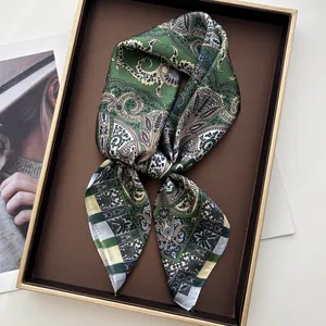 Detail of green paisley silk scarf elegantly knotted in a golden display box