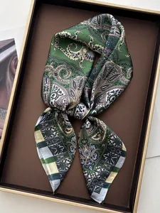 Detailed view of a green paisley silk scarf elegantly knotted in a brown display tray