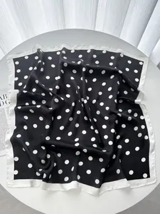Detailed view of the classic black and white polka dot silk square scarf on a table