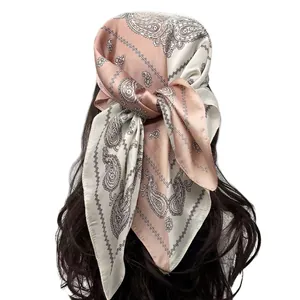 Detail of silk-satin paisley headscarf in cream and dusty pink tied on wavy hair