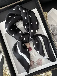 Dettaglio di un foulard in seta nero a pois bianchi con bordo a righe sottili